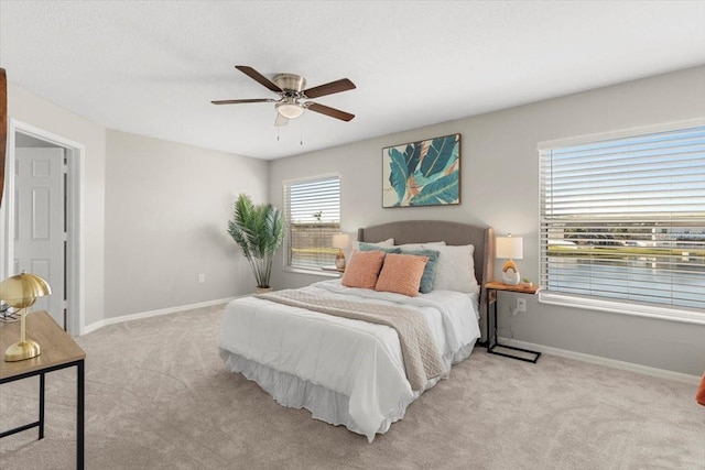 bedroom featuring multiple windows, ceiling fan, and light carpet