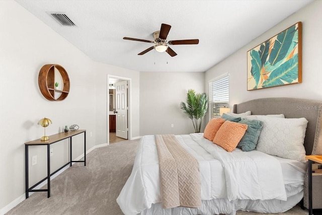 bedroom featuring light carpet, ensuite bath, and ceiling fan