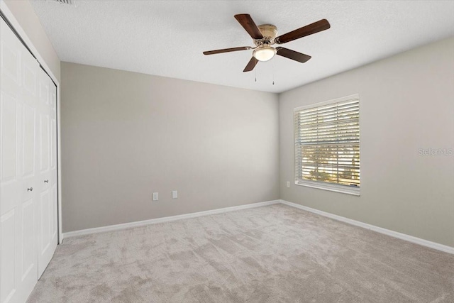 unfurnished bedroom with ceiling fan, light carpet, and a closet