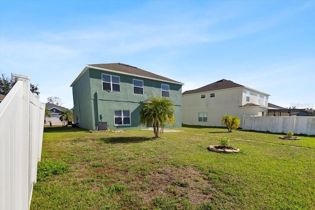 rear view of property featuring a lawn and central AC unit