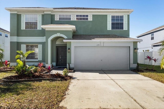 traditional-style house featuring a garage, concrete driveway, and stucco siding