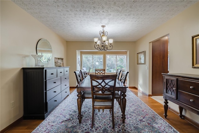 dining space featuring hardwood / wood-style floors, a textured ceiling, and a chandelier