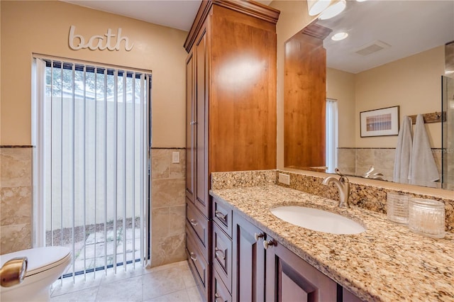 bathroom with tile patterned floors, vanity, tile walls, and toilet