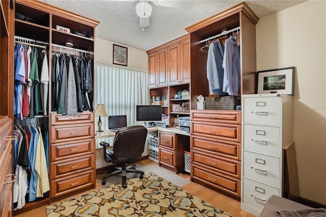 home office with ceiling fan, a textured ceiling, and light hardwood / wood-style flooring