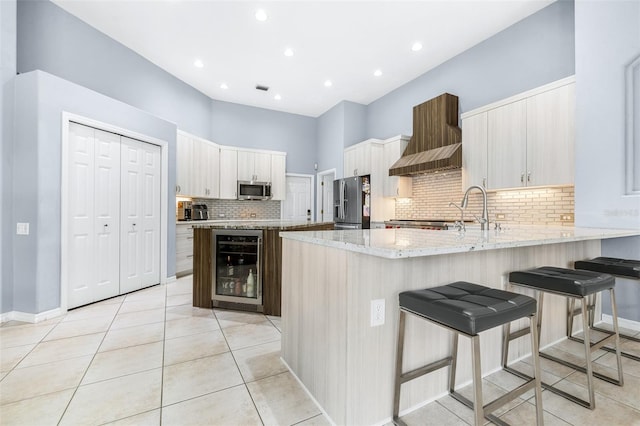 kitchen featuring premium range hood, wine cooler, decorative backsplash, a kitchen bar, and stainless steel appliances