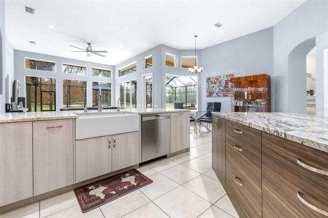 kitchen featuring stainless steel dishwasher, light stone counters, ceiling fan with notable chandelier, sink, and light tile patterned floors