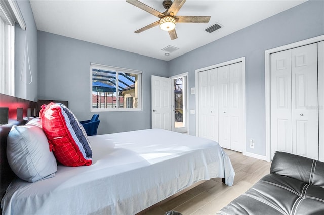 bedroom with multiple closets, ceiling fan, and light hardwood / wood-style flooring