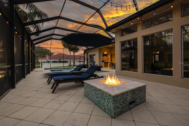 patio terrace at dusk featuring a hot tub, an outdoor fire pit, and a lanai