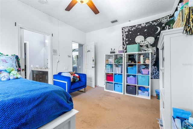 bedroom with light carpet, a textured ceiling, ensuite bath, and ceiling fan