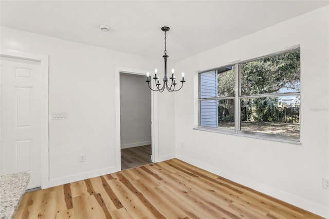 unfurnished dining area with a chandelier and hardwood / wood-style flooring