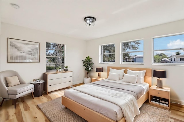 bedroom with light hardwood / wood-style floors and multiple windows