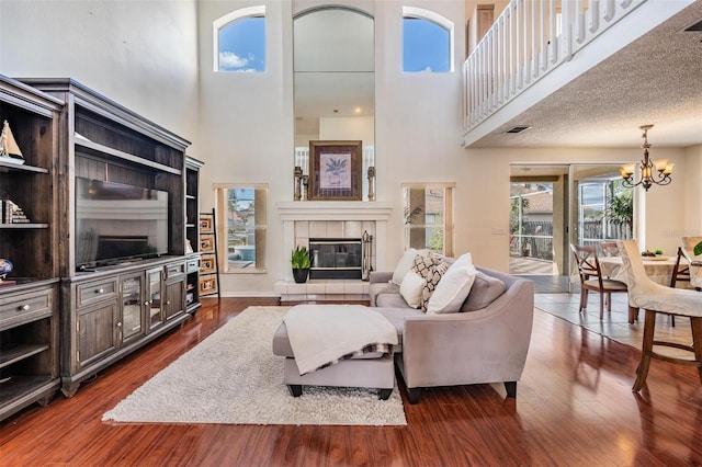 living room featuring a tile fireplace, a high ceiling, a textured ceiling, and dark hardwood / wood-style floors