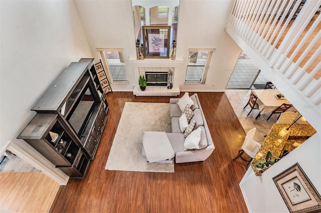 living room with hardwood / wood-style flooring, a towering ceiling, and a fireplace