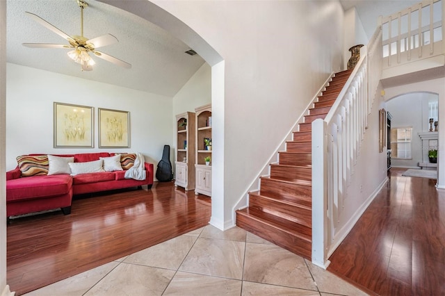 interior space with ceiling fan, high vaulted ceiling, a textured ceiling, and light wood-type flooring