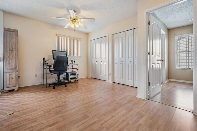 office area with ceiling fan, light wood-type flooring, and a textured ceiling