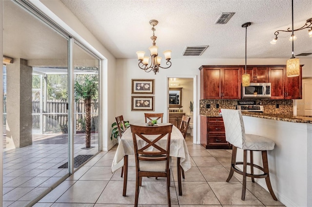 tiled dining area with a notable chandelier and a textured ceiling