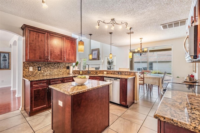 kitchen featuring a textured ceiling, kitchen peninsula, decorative light fixtures, and appliances with stainless steel finishes