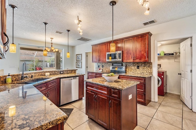 kitchen featuring sink, a center island, pendant lighting, a textured ceiling, and appliances with stainless steel finishes