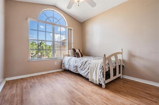 bedroom with a textured ceiling, ceiling fan, hardwood / wood-style floors, and lofted ceiling