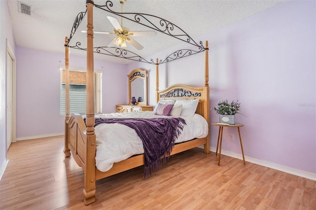 bedroom with ceiling fan, a textured ceiling, and light hardwood / wood-style flooring