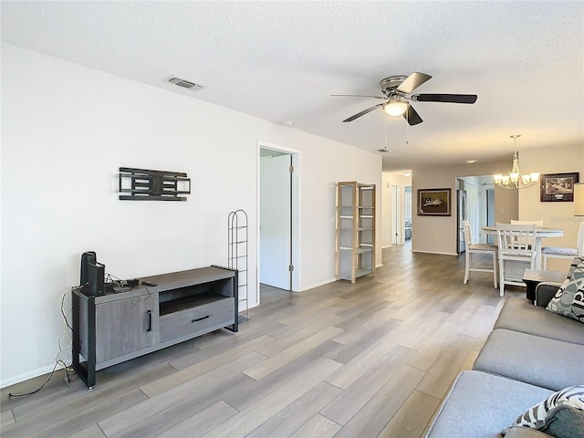 living room featuring a textured ceiling, ceiling fan with notable chandelier, and hardwood / wood-style flooring