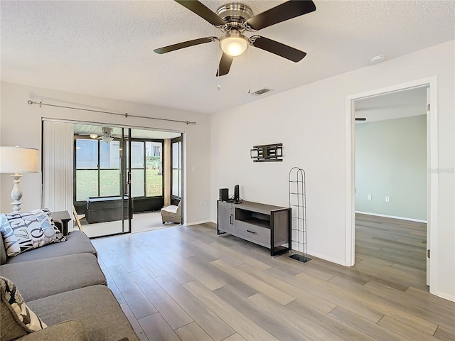 living room featuring ceiling fan, a textured ceiling, and light hardwood / wood-style flooring