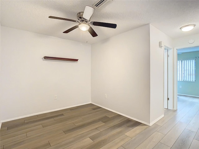 empty room with ceiling fan, a textured ceiling, and hardwood / wood-style flooring