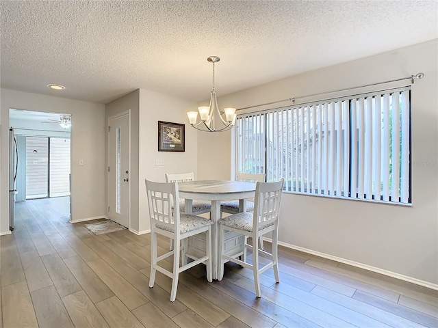 dining area with hardwood / wood-style floors, a notable chandelier, and a textured ceiling