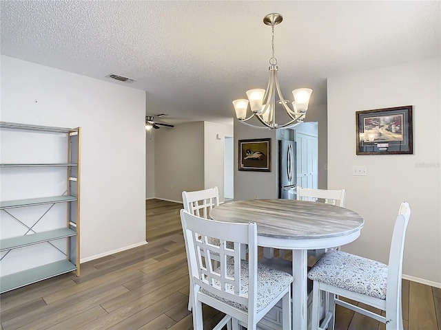 dining room with a textured ceiling, ceiling fan with notable chandelier, and hardwood / wood-style flooring