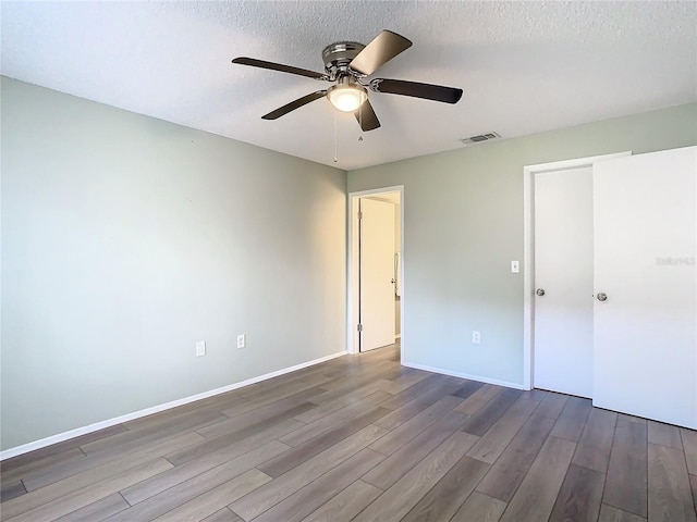 unfurnished bedroom featuring ceiling fan, wood-type flooring, and a textured ceiling