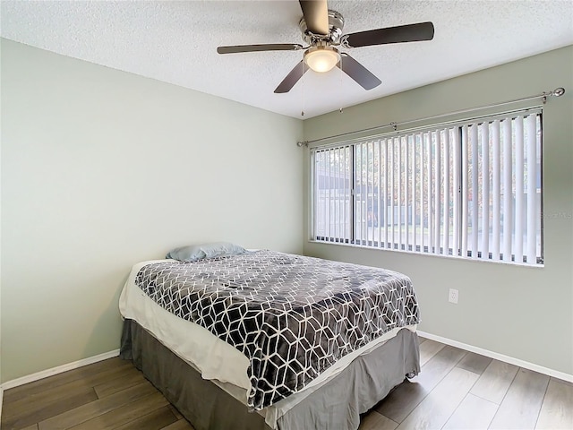 bedroom featuring ceiling fan, hardwood / wood-style floors, and a textured ceiling