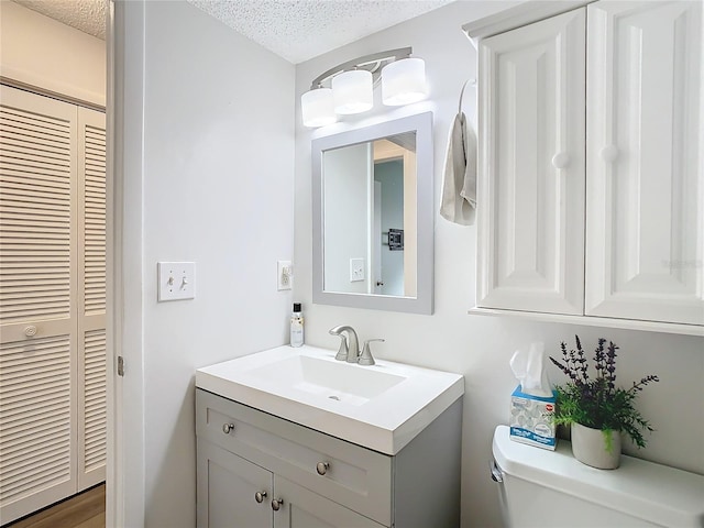 bathroom with vanity, a textured ceiling, and toilet