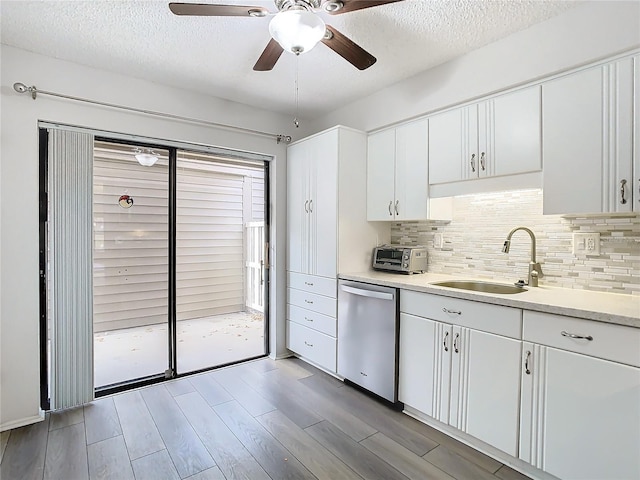 kitchen with dishwasher, white cabinets, sink, light hardwood / wood-style flooring, and a textured ceiling