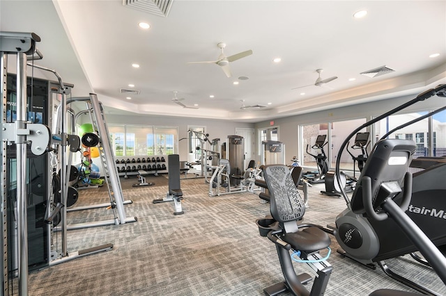 gym featuring a tray ceiling and ceiling fan