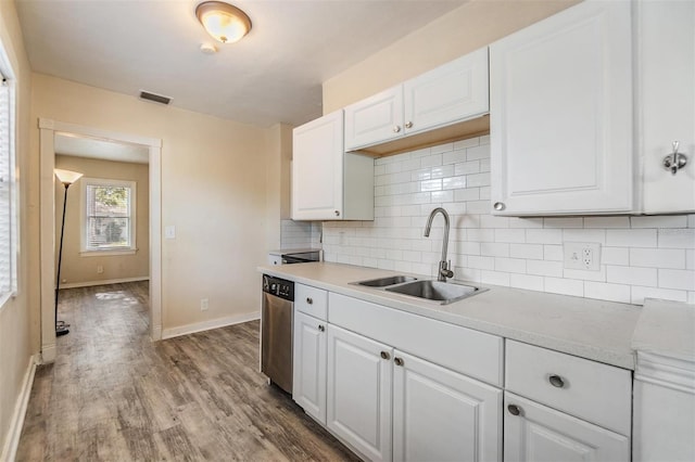 kitchen with sink, light hardwood / wood-style flooring, stainless steel dishwasher, tasteful backsplash, and white cabinetry