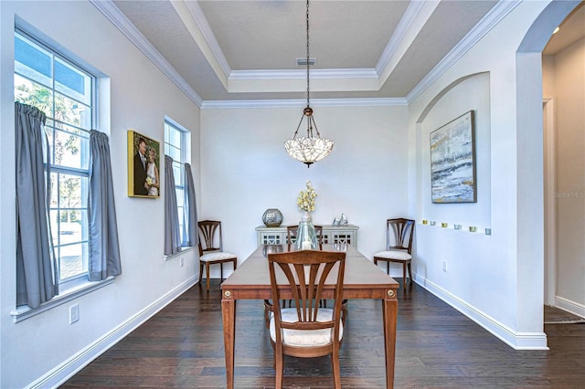 dining room with an inviting chandelier, dark hardwood / wood-style floors, a raised ceiling, and crown molding