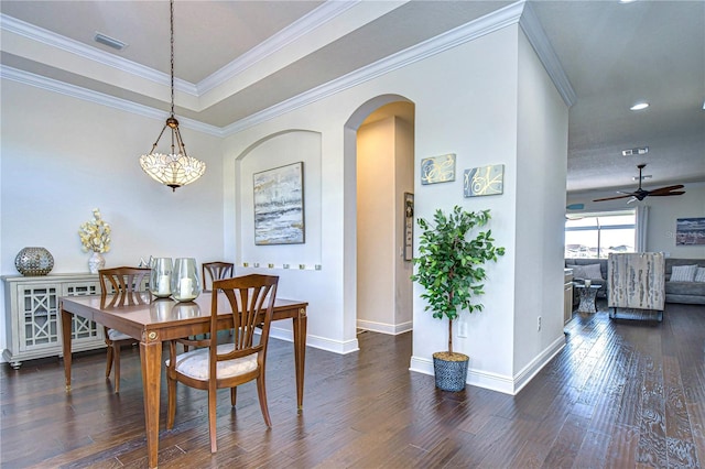 dining area with ceiling fan with notable chandelier, dark hardwood / wood-style floors, a raised ceiling, and crown molding