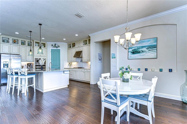 dining space featuring sink, dark hardwood / wood-style floors, a textured ceiling, and an inviting chandelier