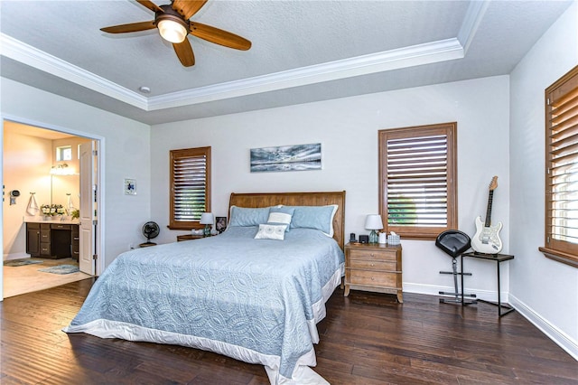 bedroom with dark hardwood / wood-style flooring, a tray ceiling, ensuite bath, and ceiling fan