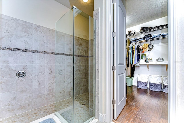 bathroom with hardwood / wood-style floors, tiled shower, and a textured ceiling