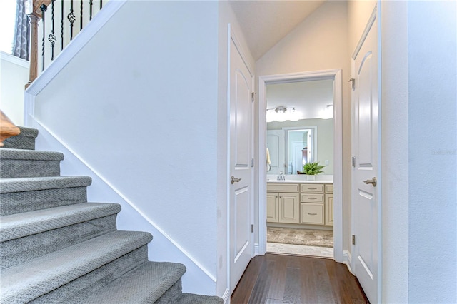 stairway featuring hardwood / wood-style floors, lofted ceiling, and sink