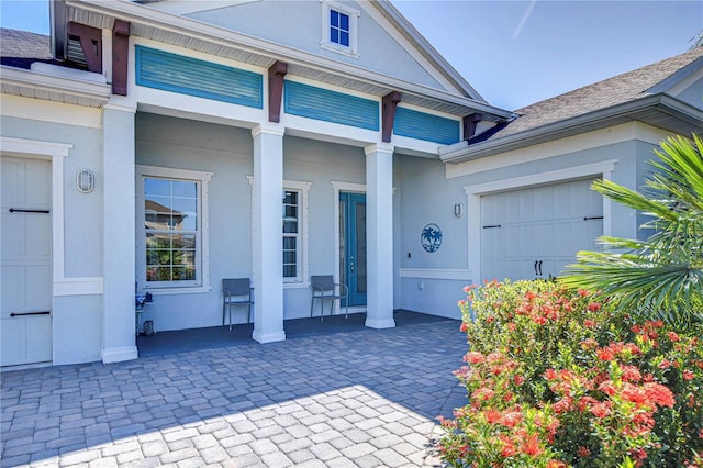 view of exterior entry with a porch and a garage