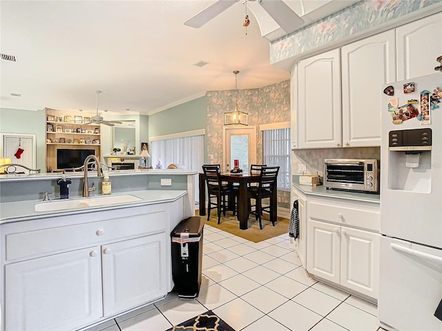 kitchen featuring white cabinetry, white fridge with ice dispenser, sink, hanging light fixtures, and light tile patterned floors