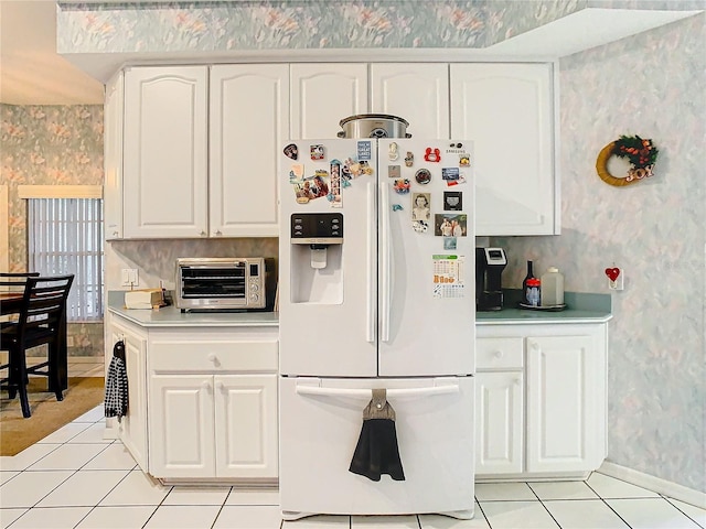 kitchen featuring white cabinetry, white refrigerator with ice dispenser, and light tile patterned floors