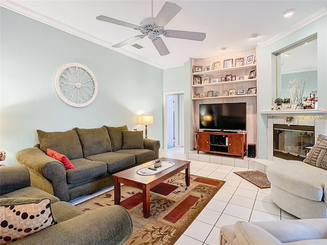 living room with ceiling fan, a fireplace, light tile patterned floors, and crown molding