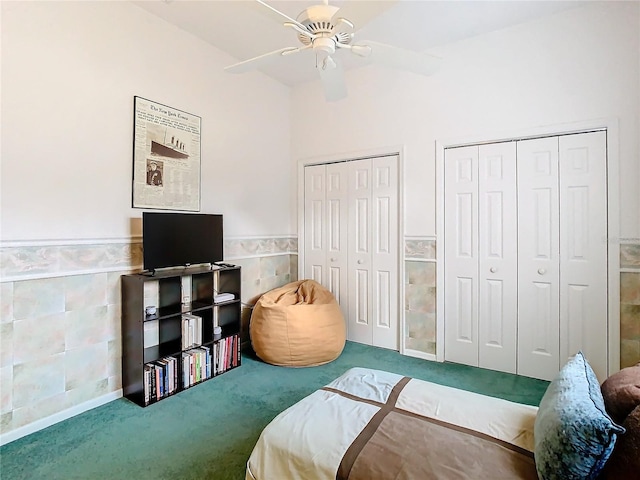 carpeted bedroom featuring ceiling fan, tile walls, and multiple closets