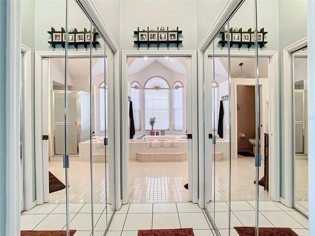 corridor featuring lofted ceiling and light tile patterned floors