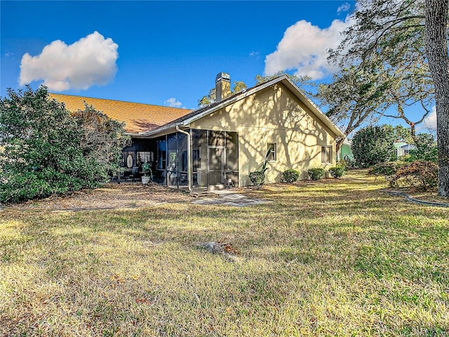 rear view of property featuring a sunroom and a lawn