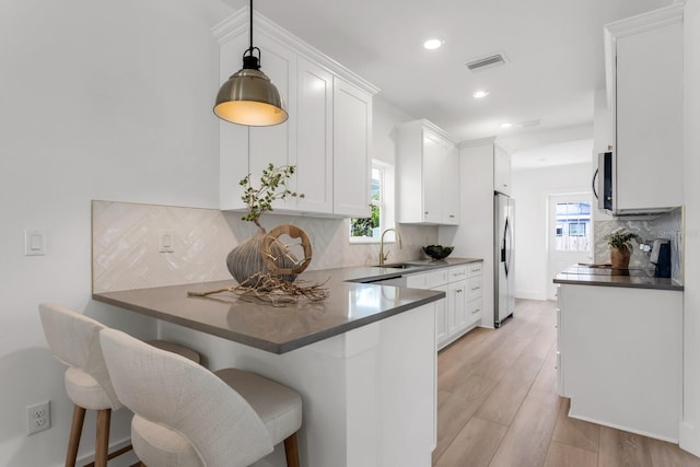 kitchen with kitchen peninsula, white cabinetry, pendant lighting, and appliances with stainless steel finishes