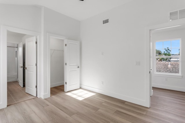 unfurnished bedroom with a walk in closet, a closet, and light hardwood / wood-style flooring